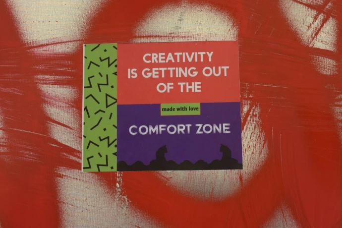 a sign on a wall that says creativity is getting out of the comfort zone